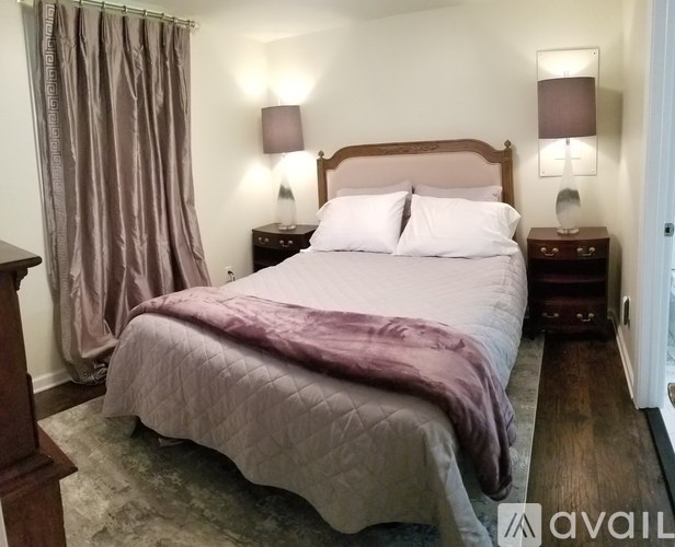 A bedroom with a large bed and two lamps on either side of the bed.