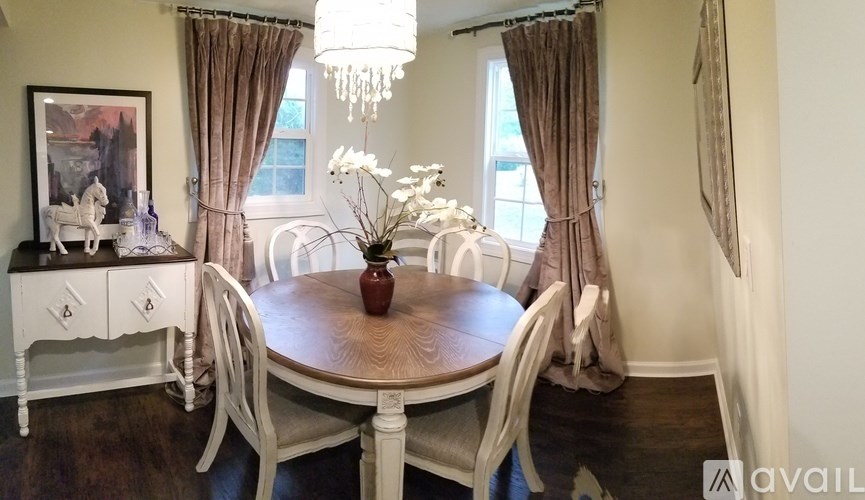 A dining room with a wooden table and white chairs.