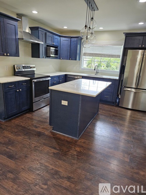 A kitchen with dark wood floors and a large island in the middle.