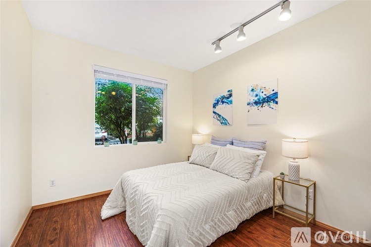 A bedroom with a large bed and a window showing trees outside.