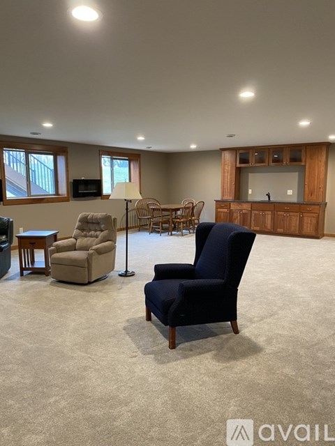 A living room with a black chair in the foreground and a wooden cabinet in the background.