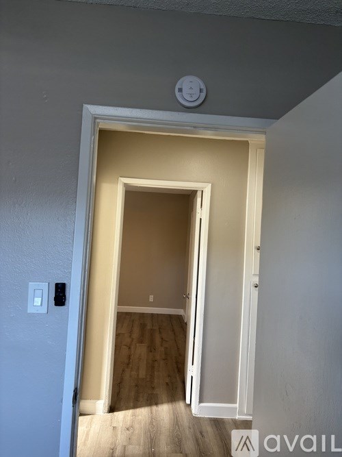 A white door is open to a room with wooden flooring.