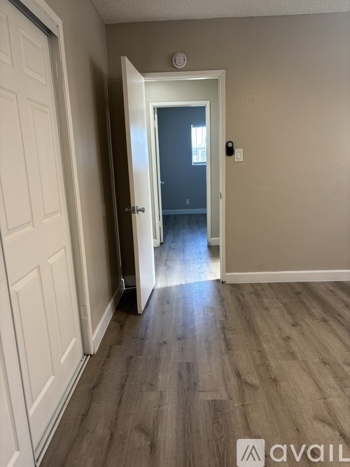 A hallway with a closed door on the left and an open door on the right.