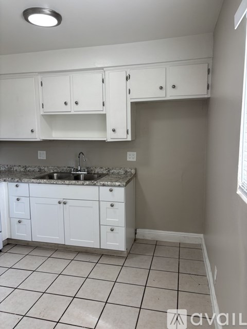 A kitchen with white cabinets and a granite countertop.