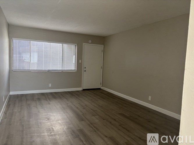 A room with wooden flooring and a window with blinds.