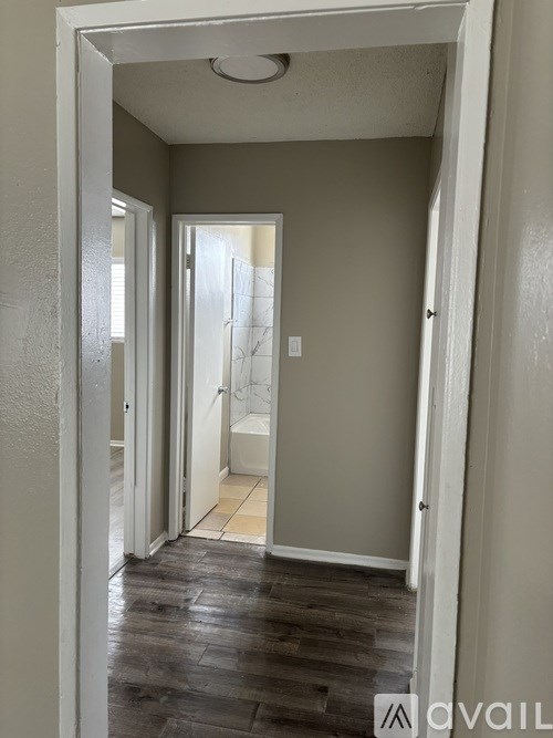 A hallway with a wooden floor and white walls.