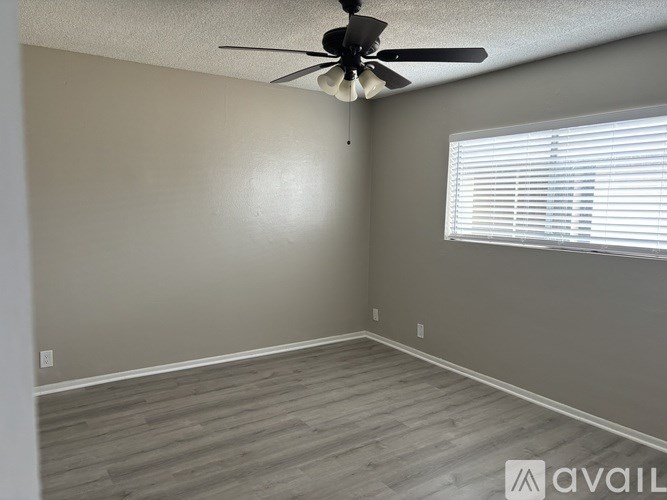 A room with a ceiling fan and a window with blinds.