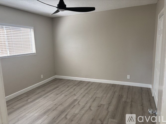 A room with a ceiling fan and a window with blinds.