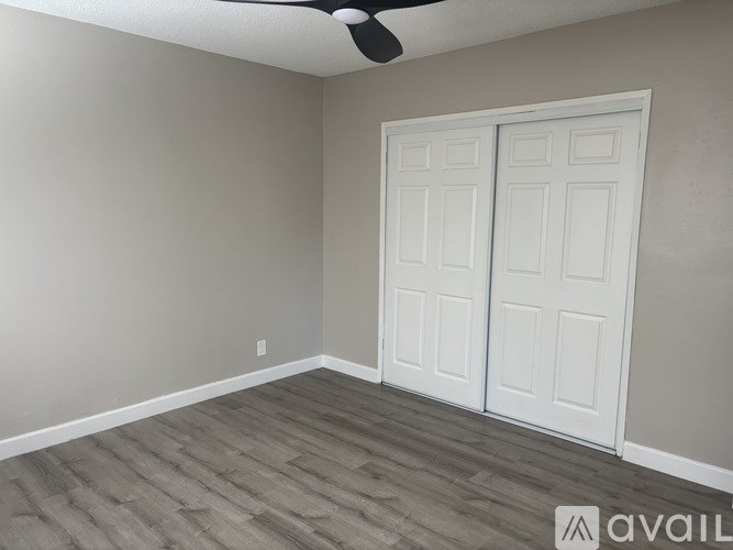 A room with a white door and a ceiling fan.