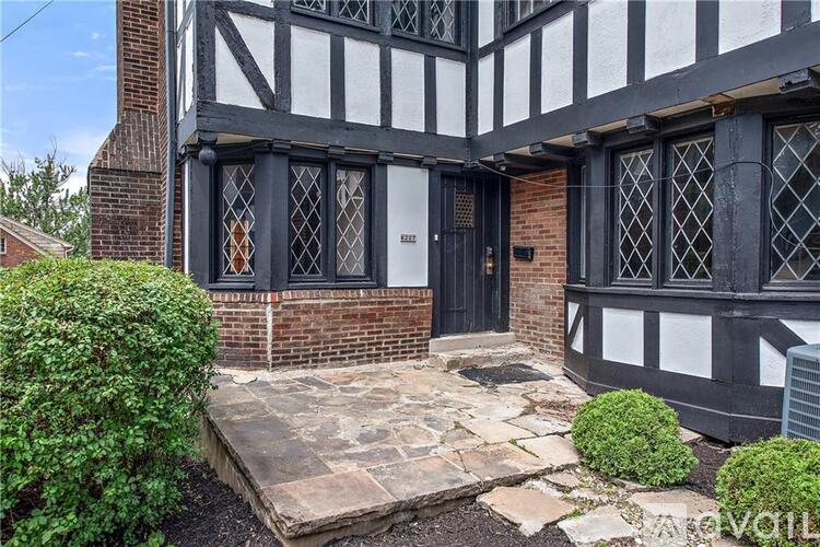 A black and white timber framed building with a brick base and a black door.