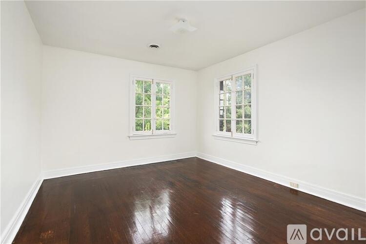 A room with wooden floors and two windows.