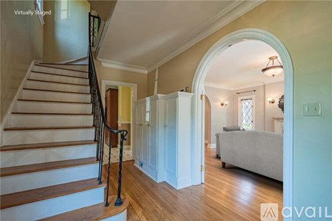 A staircase with a black railing leads to a living room with a couch and a window.