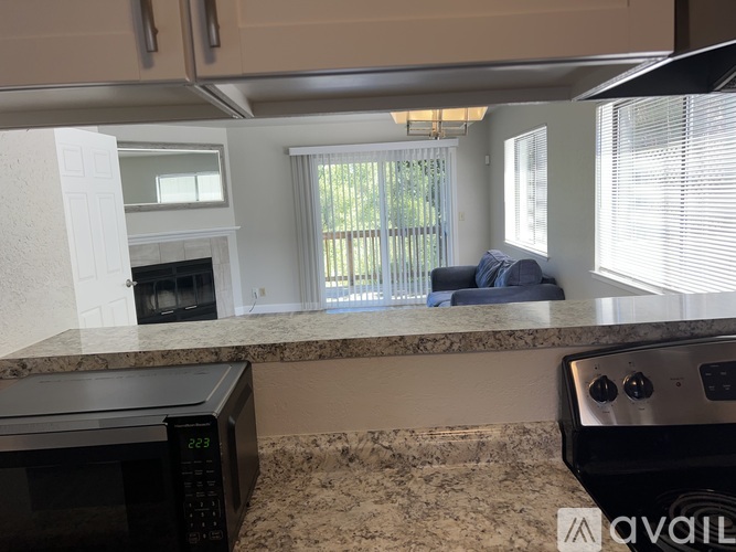 A kitchen with granite countertops and a digital clock on the microwave.