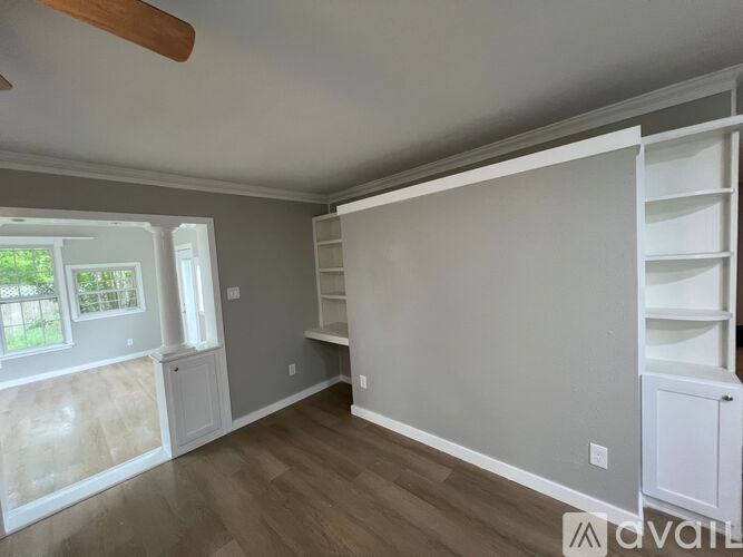 A room with a wooden floor, grey walls, and a white ceiling with a fan.