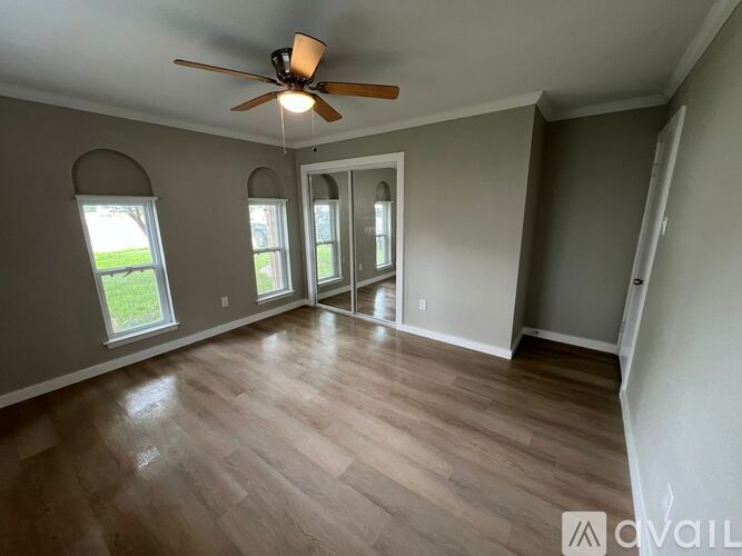 A room with a ceiling fan and wood flooring.