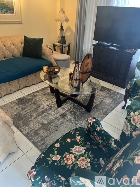 A living room with a floral rug and a grey sofa.