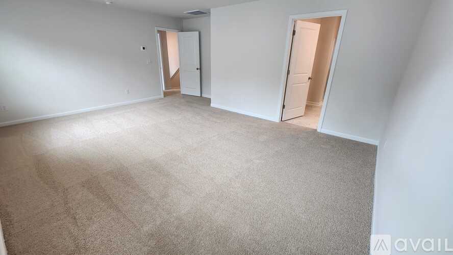 A spacious room with carpeted floor and two open doors.