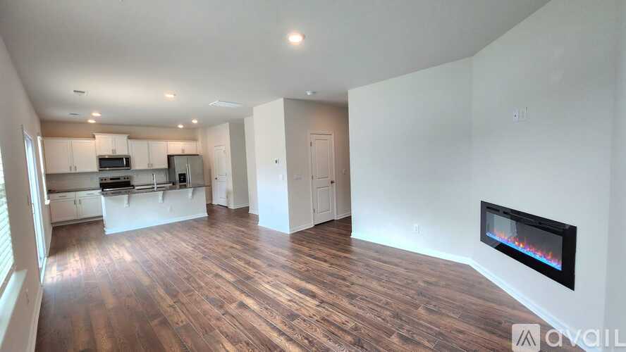 A large, empty living room with a fireplace and wooden floors.