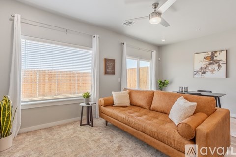 A living room with a brown couch and a ceiling fan.