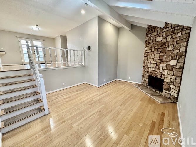 A room with wooden floors and a stone fireplace.