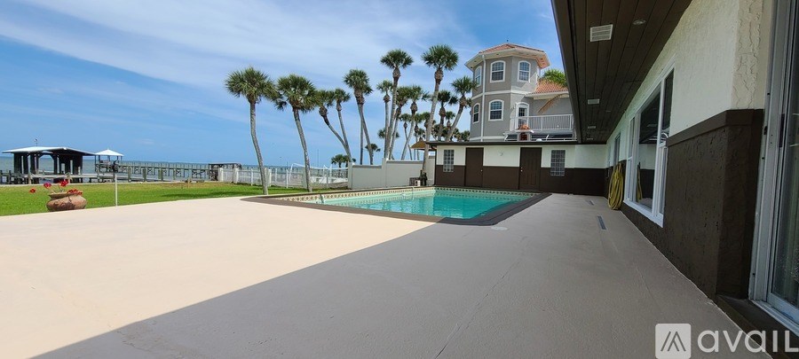 A large house with a pool and palm trees in front.
