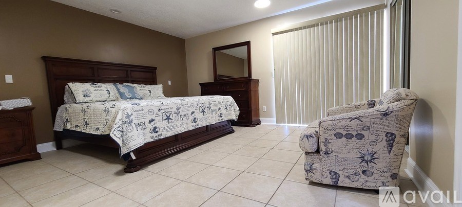 A bedroom with a bed, chair, and mirror.