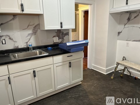 A kitchen with white cabinets and a marble backsplash.