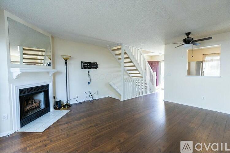 A living room with a fireplace and a staircase.