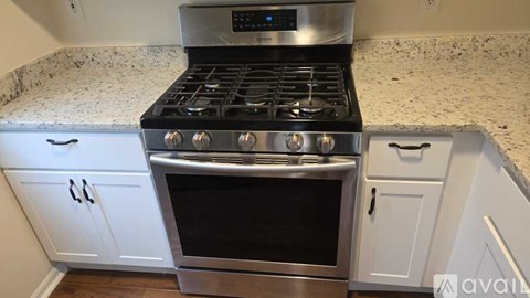 A modern kitchen with a stainless steel stove and white cabinets.