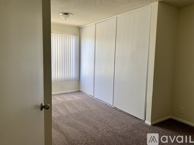 A room with a carpeted floor and a door on the left side.