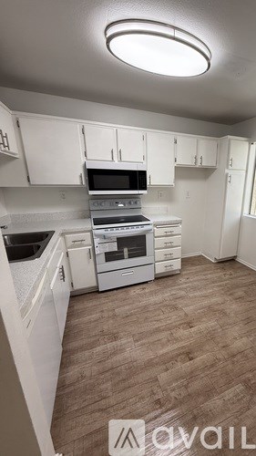 A kitchen with white cabinets and a wooden floor.