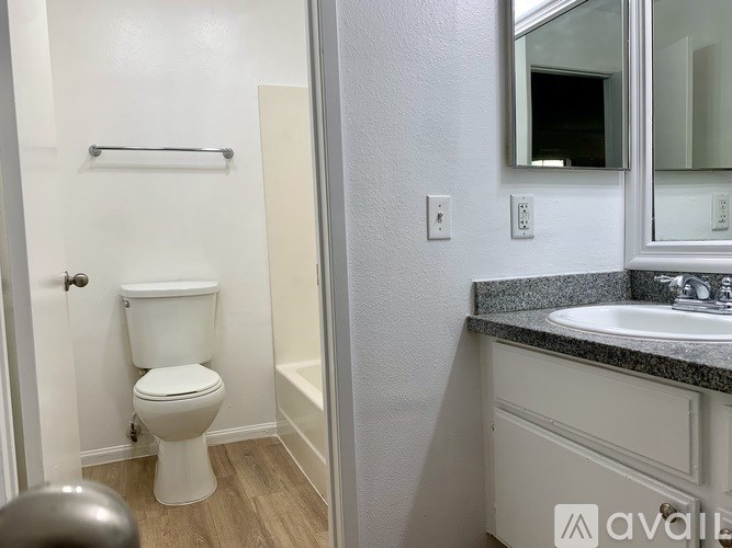A white toilet is in a small bathroom with a sink and mirror.