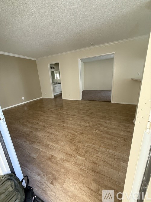 A room with wooden flooring and a washer and dryer in the background.