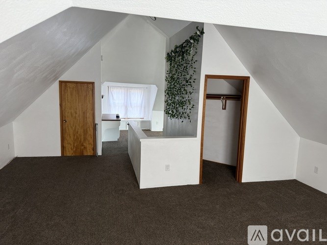 A room with a carpeted floor and a window with white curtains.