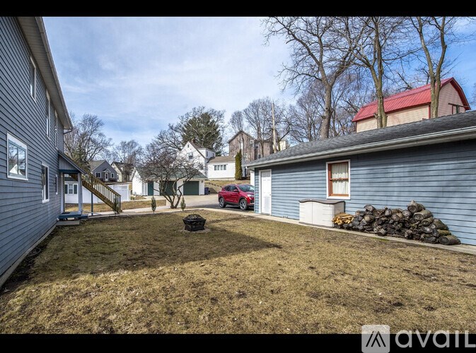 A red car is parked in front of a blue house.