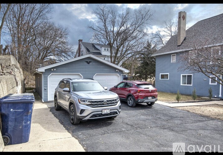 A silver SUV is parked in a driveway in front of a blue house.