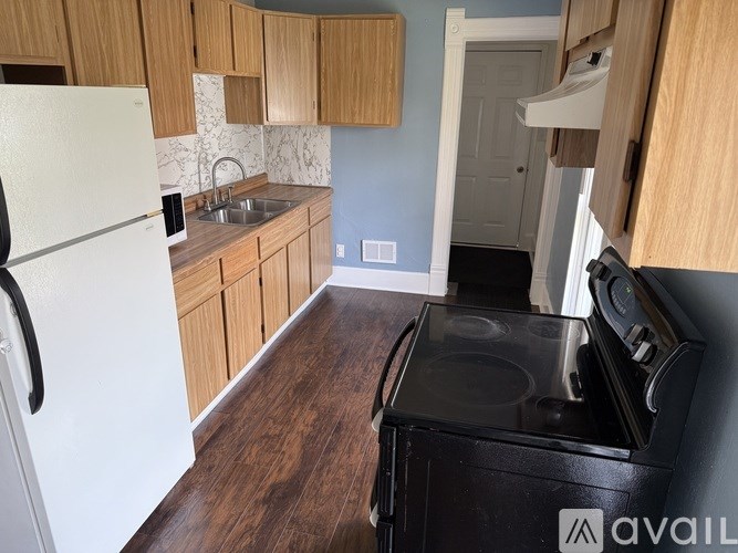 A kitchen with a white refrigerator, wooden cabinets, and a black stove top oven.