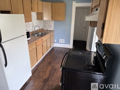 A kitchen with a white refrigerator, wooden cabinets, and a black stove top oven.