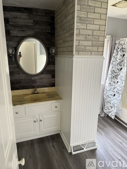 A bathroom with a round mirror and a sink.