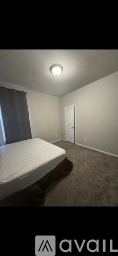 A bedroom with a bed, carpet, and a window.