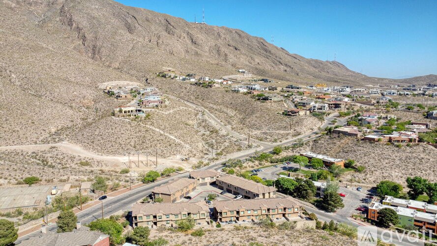 A small town with houses and buildings is situated in a valley with a mountain in the background.