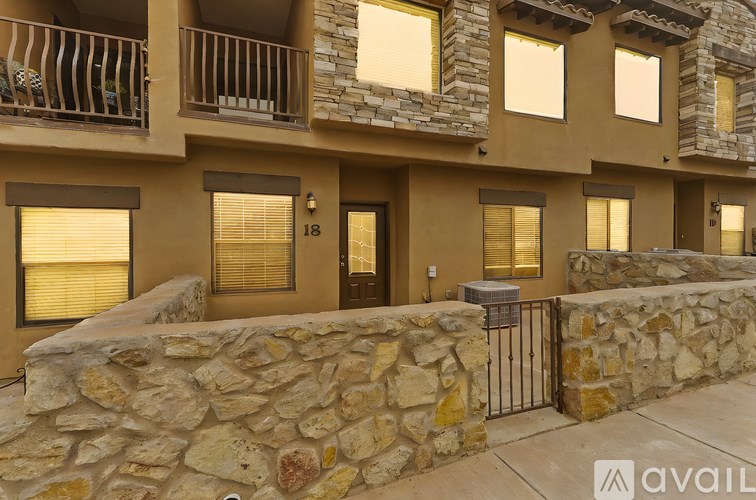 A stone wall and gate lead to a building with the number 18 on it.