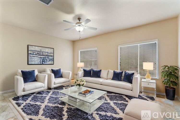 A living room with a white sofa, a glass coffee table, and a ceiling fan.