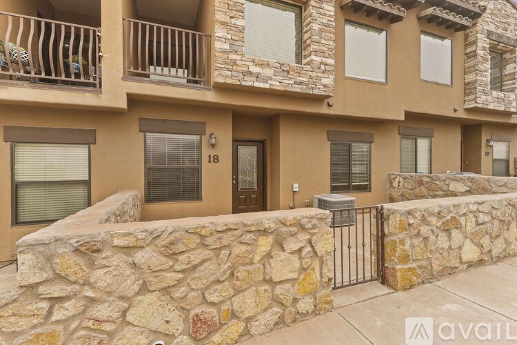 A stone wall and gate lead to a building with the number 18 on it.