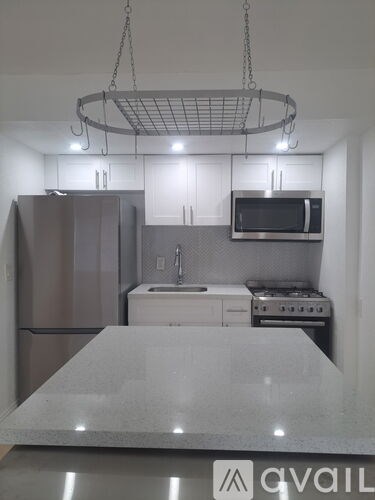 A kitchen with a refrigerator, microwave, oven, and sink.