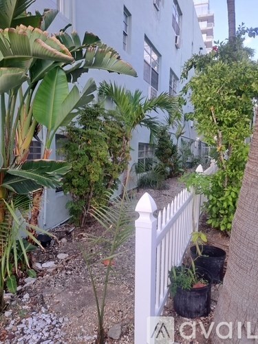 A white fence separates a garden from a building.