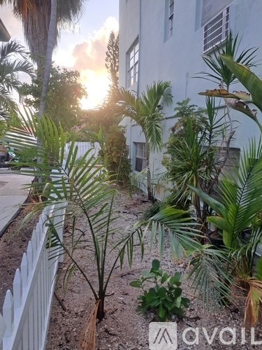 A white fence separates a garden from a building.
