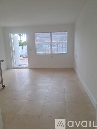 A room with a tiled floor and a window overlooking a balcony.