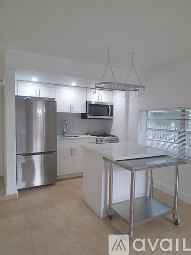 A kitchen with a refrigerator, microwave, and a stainless steel island.