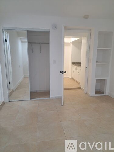 A hallway with a mirrored door and a bench.